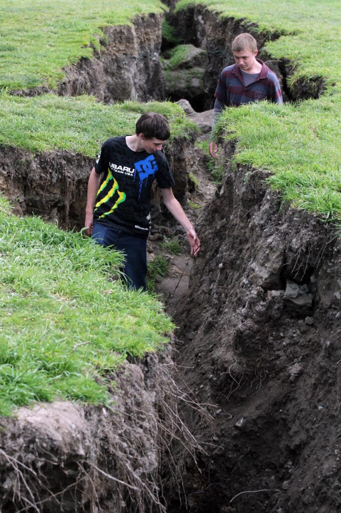 Infrastructure in Waimakariri was rebuilt after the 2010-11 Canterbury earthquakes. Pictured: Owen Trowbridge and Cameron Ellen walk through a deep crack in Kaiapoi in 2010.